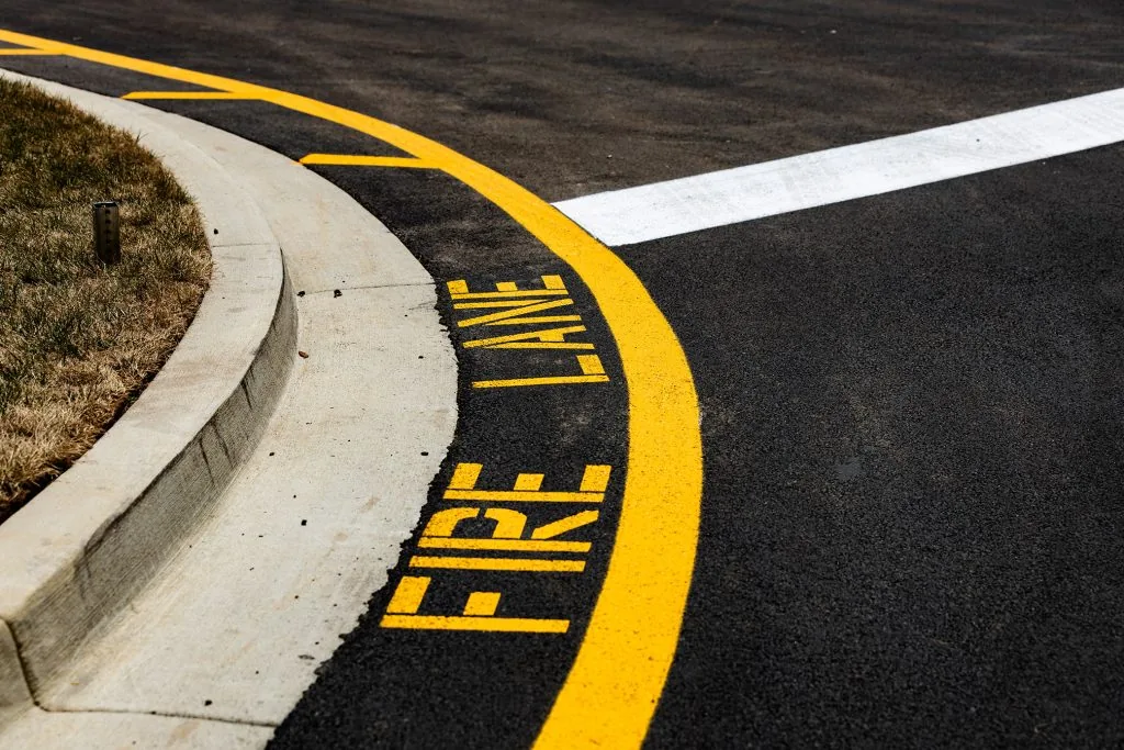 A parking lot with yellow fire lane signage on the road