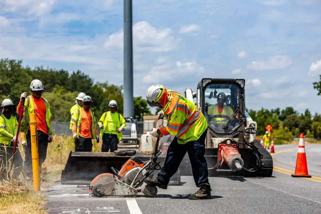 A group of men in safety vests and helmets using a machine