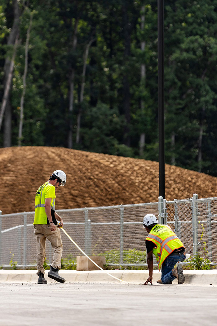 Two employees measuring a concrete curb
