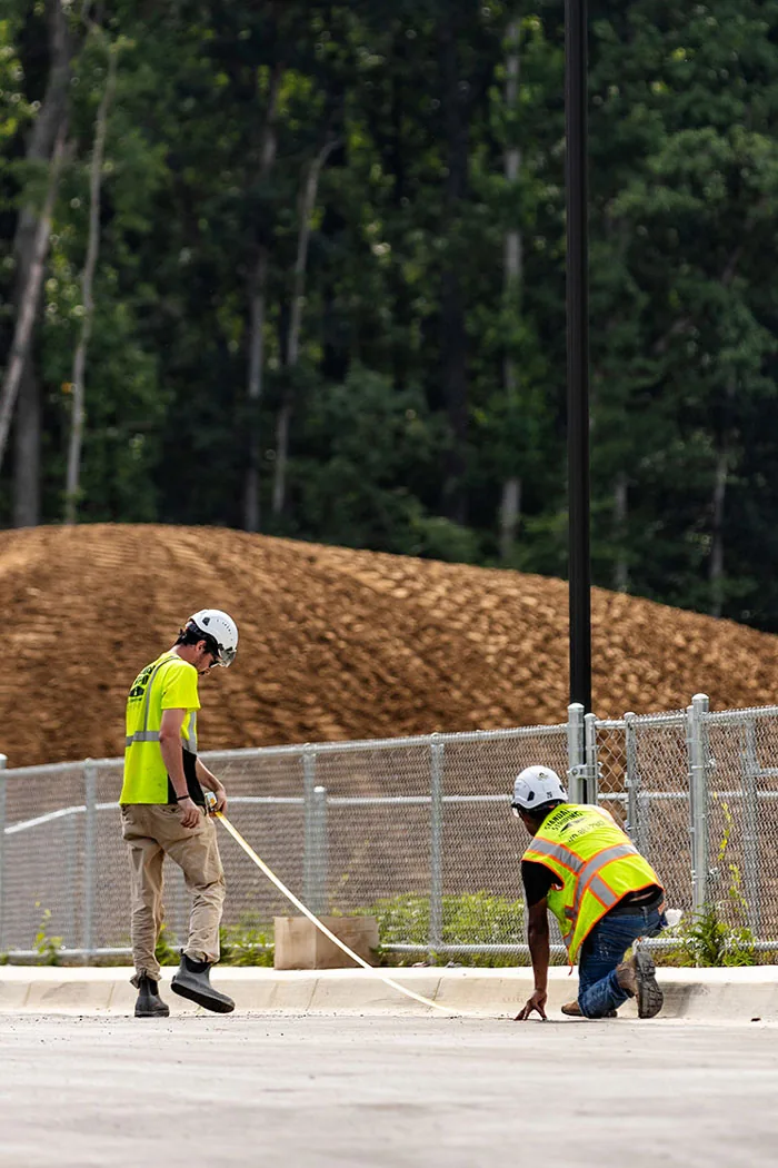 Two employees measuring a concrete curb