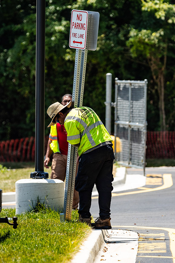 A Standard Paving & Concrete crew member installing a NO Parking sign