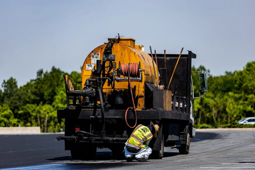 sealcoating truck applying asphalt sealcoat on commercial pavement
