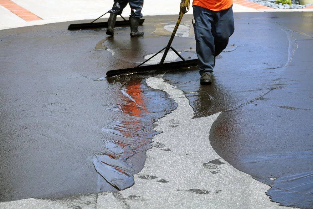 sealcoating contractor applying asphalt sealant by hand for detailed coverage